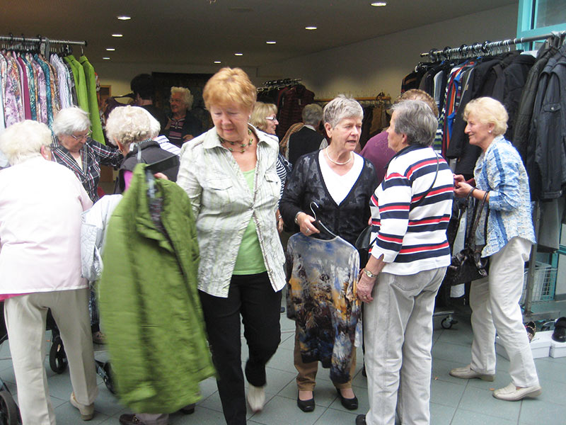 Seniorinnen stöbern gemeinsam durch die mobile Kleiderauswahl von MODE Jörger
